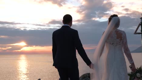 bride-and-groom-walking-near-the-sea-at-sunset