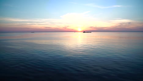 Wunderschöner-Sonnenuntergang-über-Dem-Horizont-Des-Ozeans-Mit-Booten,-Die-Vor-Der-Tiefstehenden-Sonne-Fahren,-Dramatischer-Sonnenuntergang-Vom-Kreuzfahrtschiff-Aus-Gesehen