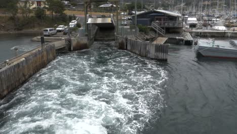 Ferry-Despega-Del-Puerto-Deportivo-Industrial-Con-Agua-Blanca-Salpicando-Desde-Popa,-Tasmania,-Australia