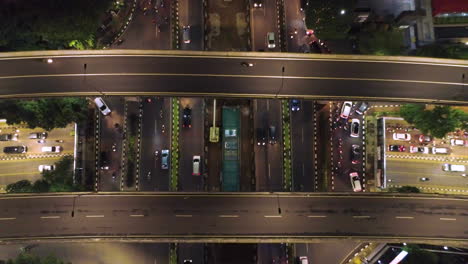 Jakarta-Kuningan-district-,-nite-time-flying,-above-and-between-building-top-shot-of-busy-intersection-in-kuningan-area,-creates-a-urban-felling-with-lots-of-traffic