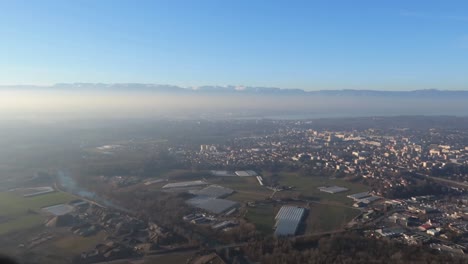 Mountain-view-of-Annemasse-and-surroundings-from-the-Salève-during-a-sunny-day-with-light-fog-and-bright-sun,-panning-right-wide-shot