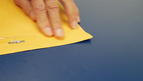 Close-up-on-hands-closing-a-yellow-envelope-with-important-document-inside-to-be-mailed-and-delivered