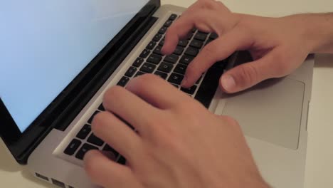 Männliche-Hände-Tippen-Auf-Der-Tastatur-Eines-Laptops-Mit-Leerem-Weißen-Bildschirm,-Mittlere-Nahaufnahme