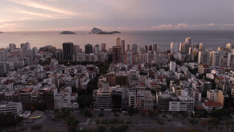 Luftaufnahme-Des-Beliebten-Und-Schicken-Strandviertels-Ipanema-In-Rio-De-Janeiro-Mit-Einigen-Inseln-Vor-Der-Küste,-Die-Bei-Sonnenaufgang-Den-Blick-Auf-Den-Stadtsee-Im-Vordergrund-Freigeben