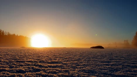 Stunning-timelapse-showing-golden-sunset-over-foggy-frozen-lake-with-winter-mist-dancing-above-the-ice,-January-in-Finland