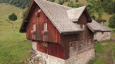 romantic-wooden-farm-house-in-the-swiss-moutains,-aerial-drone-flight
