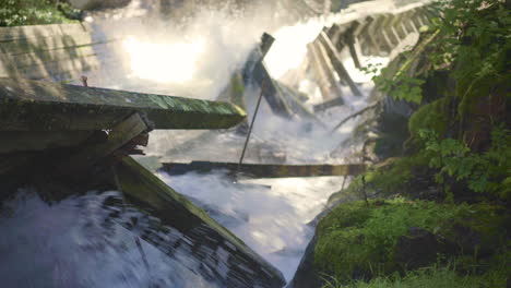 Rushing-Water-Rapids-Flowing-Down-Log-Chute-and-Crashing-Into-Damaged-Wooden-Beams-with-Mossy-Rocks-4K-ProRes
