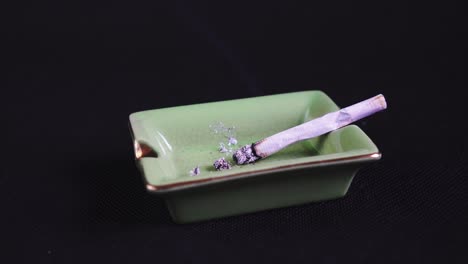Rauchen-Und-Aschen-Einer-Gerollten-Zigarette-Oder-Eines-Joints,-Legalisiertes-Marihuana-Auf-Grünem-Aschenbecher