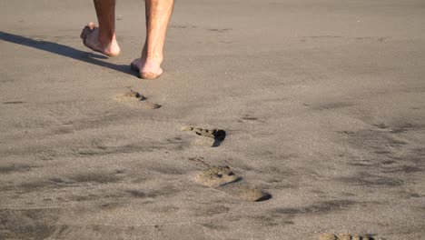 Close-up-of-feet-from-behind-walking-on-beach