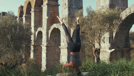 Atleta-Femenina-Realizando-Yoga-De-Cabeza-En-El-Antiguo-Acueducto
