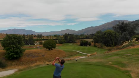 SLOWMO---Male-golf-player-hitting-ball-at-golf-course-in-New-Zealand---Aerial