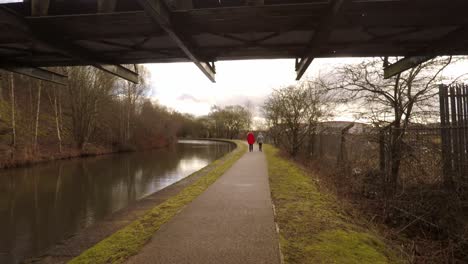 2-women-take-a-walk-along-by-the-former-industrial-canal-in-Stoke-on-Trent,-a-poverty-stricken-area-featuring-many-factories-in-ruins-along-by-the-canal