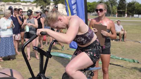 Atleta-Femenina-Compitiendo-Duro-En-Una-Bicicleta-De-Aire-En-Una-Competencia-De-Cross-Fit