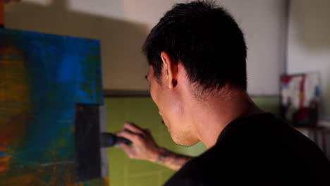 Chinese-man-painting-making-art-in-studio-with-dramatic-lighting