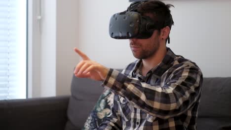 A-medium-shot-of-a-white-young-male-playing-virtual-reality-while-sitting-on-a-couch-without-controllers