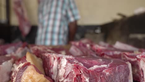 Butcher-in-meat-market-saws-and-chops-fresh-steaks-arranged-for-sale