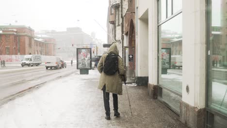 Man-with-crutch,-walking-through-snow-in-Helsinki