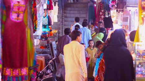 Ein-Blick-Auf-Den-Pakistanischen-Markt-In-Der-Eid-Saison,-Frauen-In-Burkas,-Männer-In-Shalwar-Kamiz,-Nachtmarktstraße-Mit-Damenkleidern
