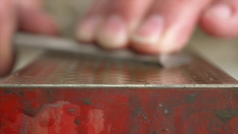 A-rack-focus-Macro-Shot-of-a-Chisel-being-sharpened-on-a-Whetstone-by-a-Carpenter