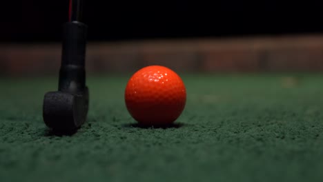 Ein-Minigolf-Putter,-Extreme-Nahaufnahme-Eines-Orangefarbenen-Golfballs