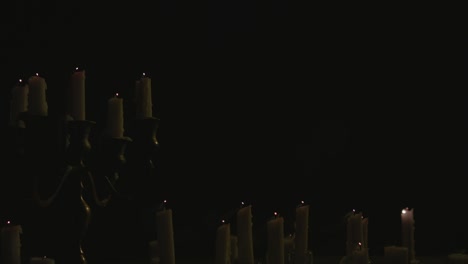 Eine-Gruppe-Weißer-Kerzen,-Einige-Auf-Einem-Kandelaber,-Die-Angezündet-Und-Dann-Vom-Wind-In-Zeitlupe-Ausgeblasen-Werden