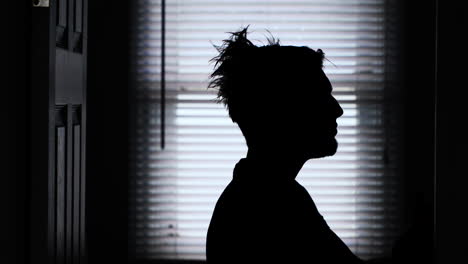 A-young-man's-long-messy-hair-being-combed-down-and-styled-in-a-backlit-silhouette-4K-static-shot