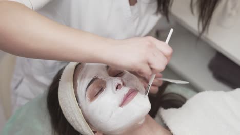 Professional-cosmetician-applying-face-mask-to-a-customer