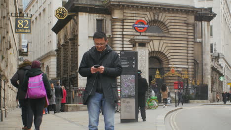 Emotionaler-Asiatischer-Mann,-Der-In-Der-Öffentlichkeit-Im-Finanzviertel-Von-London-SMS-Schreibt