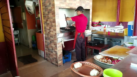 Chef-In-Red-Apron-Cooking-Beef-On-An-Open-Grill-Outside-In-A-Restaurant-In-Mexico
