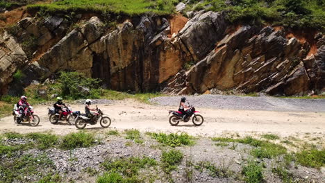Slow-motion-drone-side-view-of-a-group-of-motorcyclists-taking-off-after-resting-along-the-Ma-Pi-Leng-Pass,-Vietnam