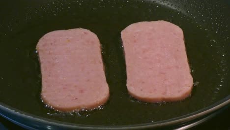 Spam-sizzling-in-a-frying-pan-cooking-a-High-cholesterol-English-breakfast-unhealthy-eating