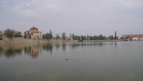 Wide-establishing-shot-of-Tata-Castle-at-the-shore-of-Öreg-Lake,-Tata,-Hungary---Panning-right-to-left