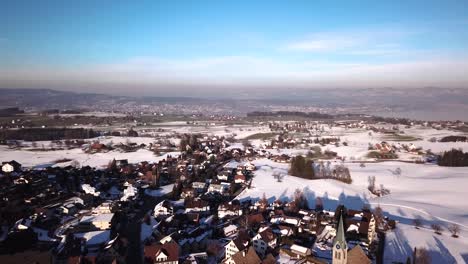Beautiful-aerial-view-over-a-small-village-on-a-hill-next-to-the-lake-of-zurich