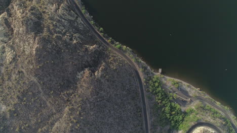 AERIAL---Overhead-Drone-Shot-of-Road-Next-to-Lake