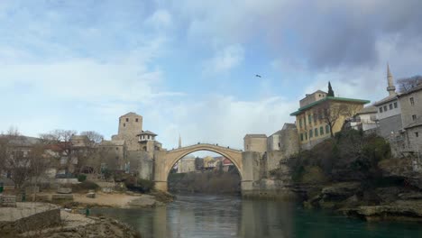 Weitwinkelaufnahme-Der-Alten-Brücke-über-Den-Fluss-Neretva-Und-Flankiert-Von-Den-Häusern-In-Der-Altstadt-Von-Mostar