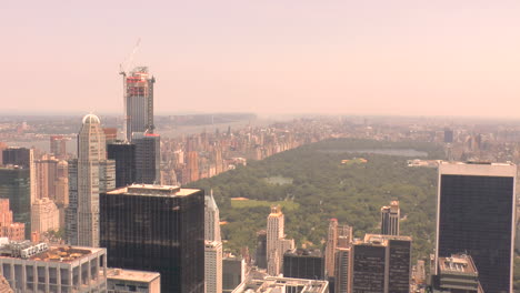 Zoom-out,-View-of-Central-Park-and-buildings-and-skyscrapers-in-Manhattan,-New-York-City