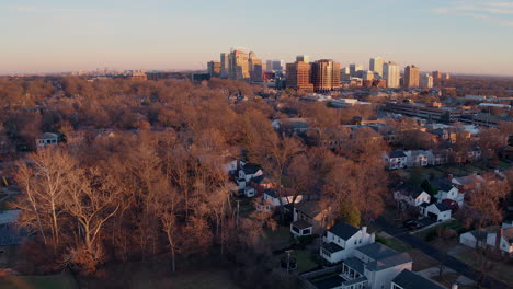 Aerial-fly-away-from-Clayton-city-skyline-and-over-houses-at-sunset