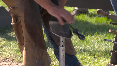 A-farrier-shoeing-a-dark-brown-horse-at-an-equestrian-competition