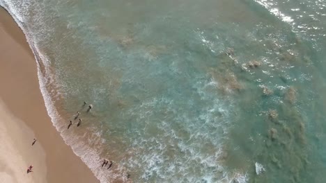 360-Grad-Luftaufnahme-Von-Wellen,-Die-Ans-Ufer-Schlagen,-Und-Badenden-Menschen