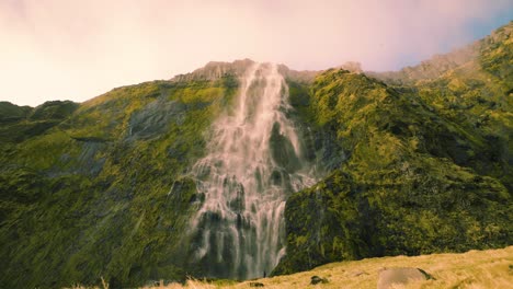 Ruhiger-Wasserfall-Mit-Sauberem-Quellwasser,-Das-Eine-Klippe-Mit-Moosbedeckten-Felsen-Hinunterfließt