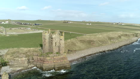 Aerial-rising-shot-moving-from-a-low-to-high-angle-of-Keiss-Castle-on-a-sunny-day,-Caithness,-Scotland
