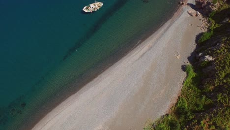 Aerial:-A-quiet-beach-with-a-fishing-boat-on-Lesbos,-near-Turkey