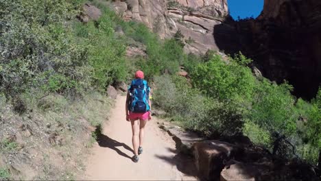 Young-woman-wearing-backpack-is-walking-to-Angel's-Landing-in-Zion-National-park-in-Utah,-USA