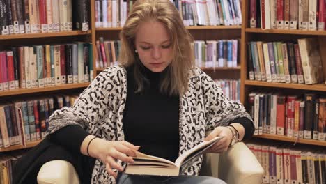 Panning-down-shot-of-girl-reading-book-in-library