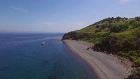 Aerial:-A-quiet-beach-with-a-fishing-boat-on-Lesbos,-near-Turkey