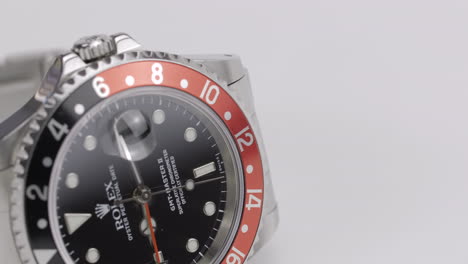 Beautiful-Rolex-GMT-Master-II-Cocke-timepiece,-rotating-on-a-white-display,-shot-with-a-macro-lens