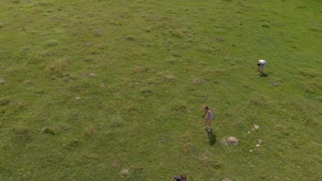 Children-run-and-play-in-green-field---aerial-shot