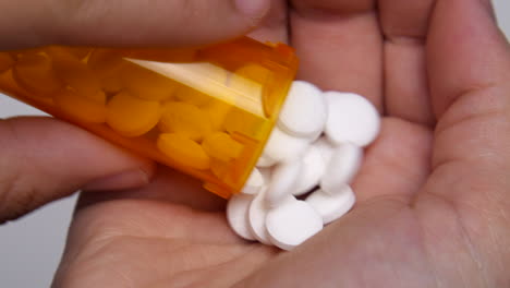 Doctor-pours-out-bottle-full-of-pills-onto-their-hand