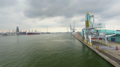 Flying-backwards-frone-footage-in-the-port-of-Antwerp,-Scheldt-river,-cargo-ships,-machinery,-granite-blocks,-containers,-far-view-from-the-nuclear-station-in-Doel