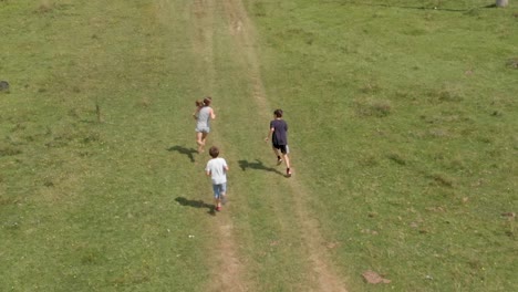Children-run-and-play-in-green-field---aerial-slow-motion